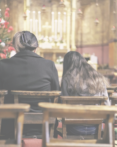 Two people sitting in a church pew facing the altar.
